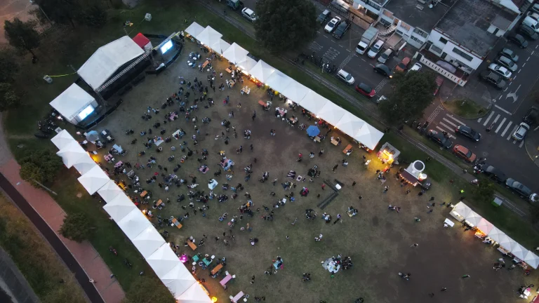 Vista aérea del Burger Picnic Modelia 2026 en Bogotá, con carpas de hamburgueserías y cervecerías, público y tarima principal del evento.